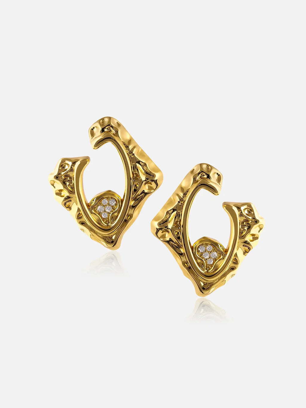 Pair of Tactilery Baroque Frame Stud Earrings in polished gold on a light grey background, the angular diamond-shaped C-hoop with heavily textured molten baroque surface, open center frame, and a small pavé zircon quatrefoil accent at the lower inner corner, shown in three-quarter view