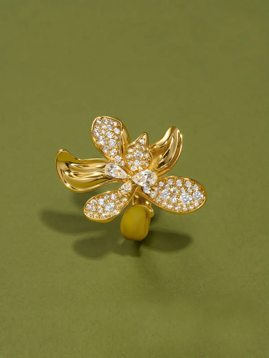Tactilery Blossom Ring displayed upright on a white background showing the full front face of the oversized gold five-petal orchid flower with three fully pavé zircon upper petals, central prong-set round zircon, and two smooth polished gold lower petals with ribbed vein texture, on a wide tapered gold band
