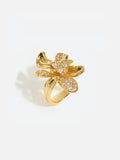 Tactilery Blossom Ring in polished gold on a white background, the oversized five-petal orchid flower cocktail ring with three fully pavé zircon upper petals, a central prong-set round zircon, and two smooth polished gold lower petals with ribbed vein texture, on a wide tapered gold band