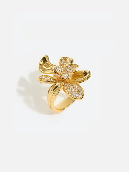 Tactilery Blossom Ring in polished gold on a white background, the oversized five-petal orchid flower cocktail ring with three fully pavé zircon upper petals, a central prong-set round zircon, and two smooth polished gold lower petals with ribbed vein texture, on a wide tapered gold band