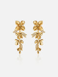 Pair of Tactilery Tassel Detachable Drop Earrings in polished gold on a light grey background, the long cascading drop composed of a large five-petal blossom flower stud top with smooth domed petals and pavé zircon stamens, a detachable lower section with a smaller five-petal blossom flower and a trailing spray of polished gold oval leaf buds with pavé zircon leaf accents, shown assembled as a full drop