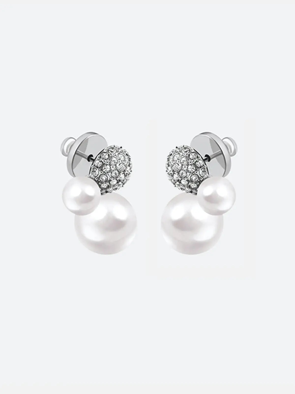 Pair of Tactilery Bubble Stud Earrings in silver shown from the back on a light grey background, the silver disc butterfly backs and silver post pins visible at top, with the large white pearl spheres and small white pearl spheres extending below