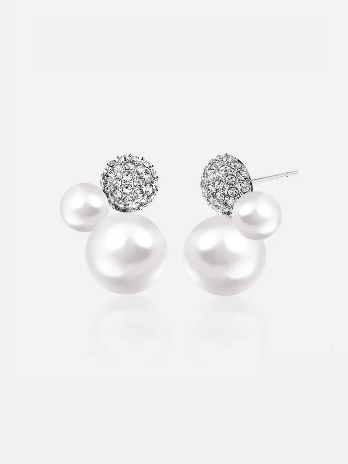 Pair of Tactilery Bubble Stud Earrings in silver on a light grey background, the cluster stud with a fully pavé zircon dome sphere at top, a small white pearl sphere at mid-right, and a large white pearl sphere at bottom, with silver post pins