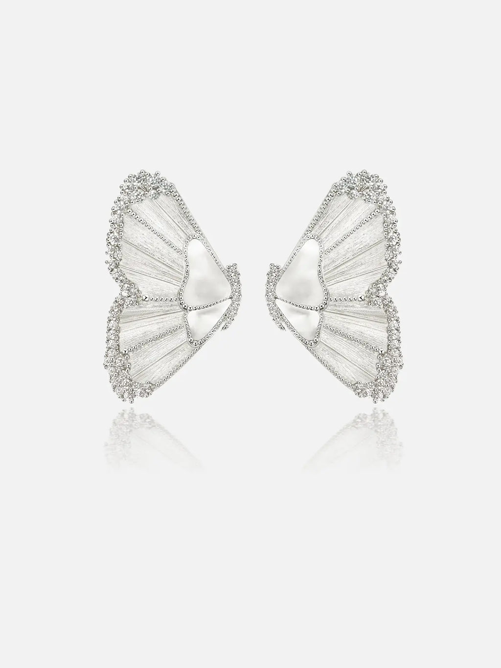 Pair of Tactilery Butterfly Wing Earrings in silver on a light grey background, the large sculptural half-butterfly wing stud with translucent white mother-of-pearl shell wing panels divided by fine silver wire veins, fully pavé zircon border edging the entire wing silhouette, and a smooth white shell triangular body center, with silver post pins