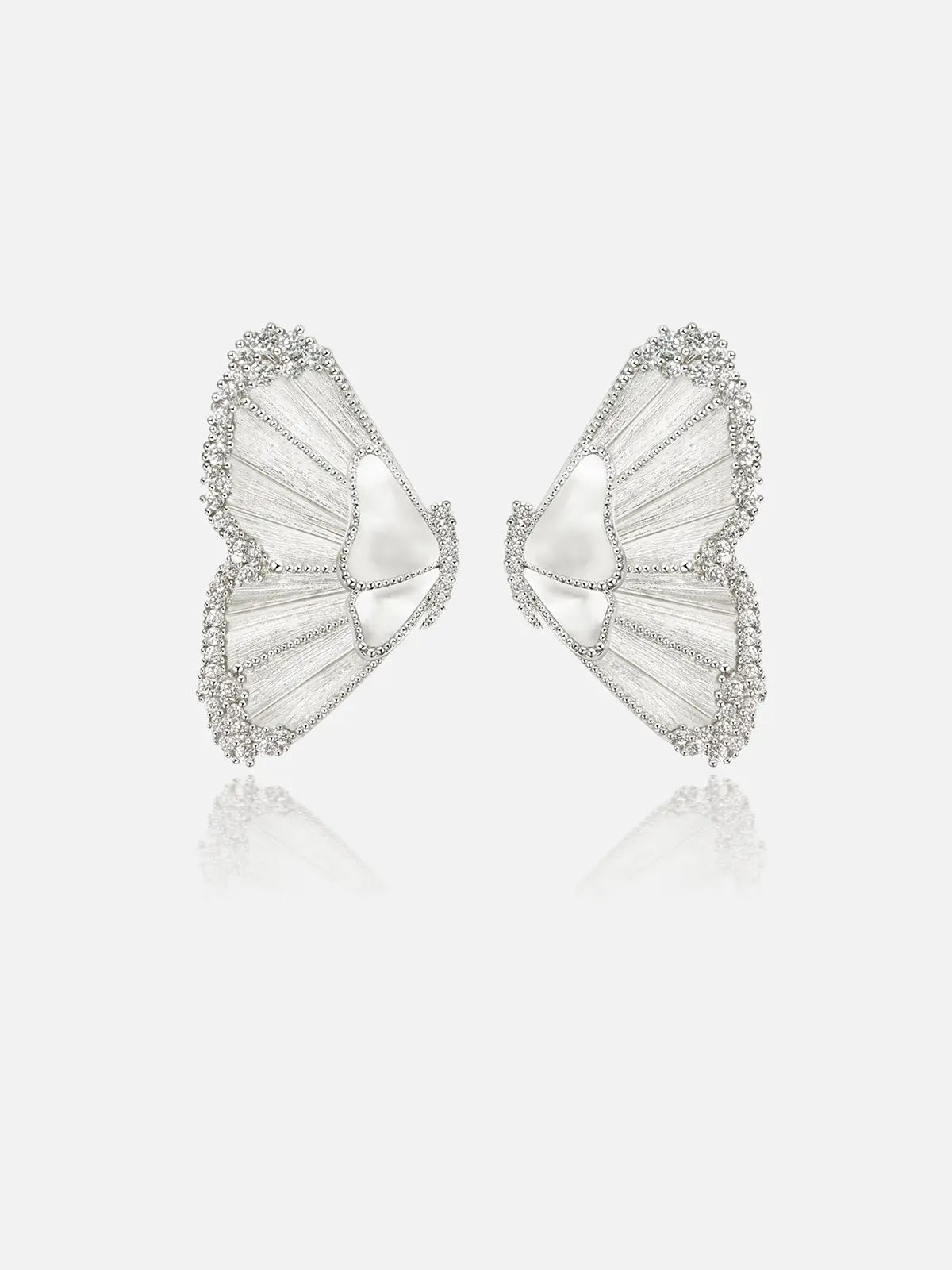 Pair of Tactilery Butterfly Wing Earrings in silver on a light grey background, the large sculptural half-butterfly wing stud with translucent white mother-of-pearl shell wing panels divided by fine silver wire veins, fully pavé zircon border edging the entire wing silhouette, and a smooth white shell triangular body center, with silver post pins