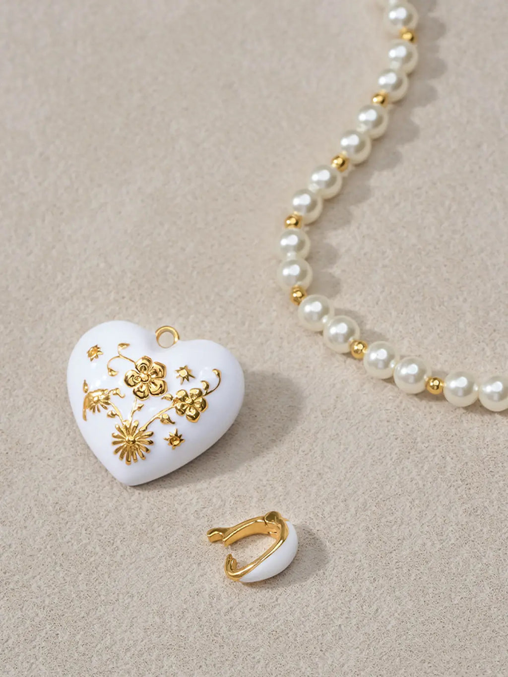 Extreme close-up of the Tactilery Garden Floral Pearl Necklace central pendant on a warm cream surface, the sculptural polished gold five-petal flower with deeply line-engraved radiating sunburst petal surfaces and central prong-set round zircon in sharp detail, with the graduated freshwater pearl strand and small polished gold seed bead spacers visible on either side