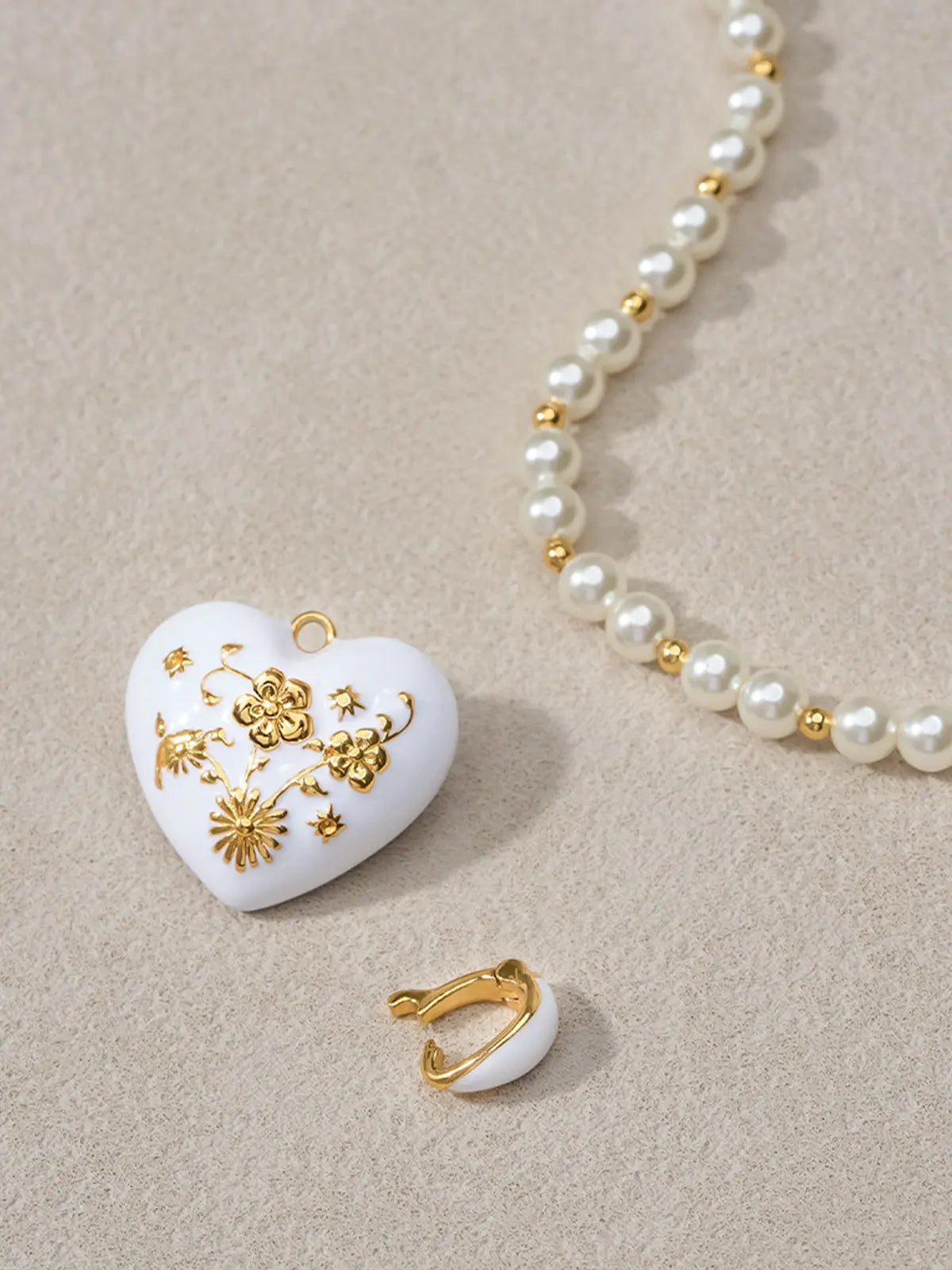 Extreme close-up of the Tactilery Garden Floral Pearl Necklace central pendant on a warm cream surface, the sculptural polished gold five-petal flower with deeply line-engraved radiating sunburst petal surfaces and central prong-set round zircon in sharp detail, with the graduated freshwater pearl strand and small polished gold seed bead spacers visible on either side
