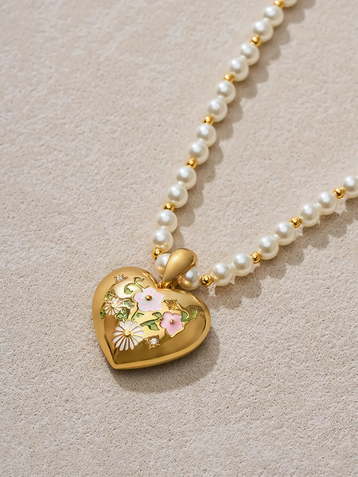 Flat-lay detail of the Tactilery Garden Floral Pearl Necklace on a warm cream surface, the sculptural polished gold five-petal sunburst flower pendant with prong-set round zircon shown alongside the graduated freshwater pearl strand and small polished gold seed bead spacers, the graduating pearl size and bead pattern clearly visible