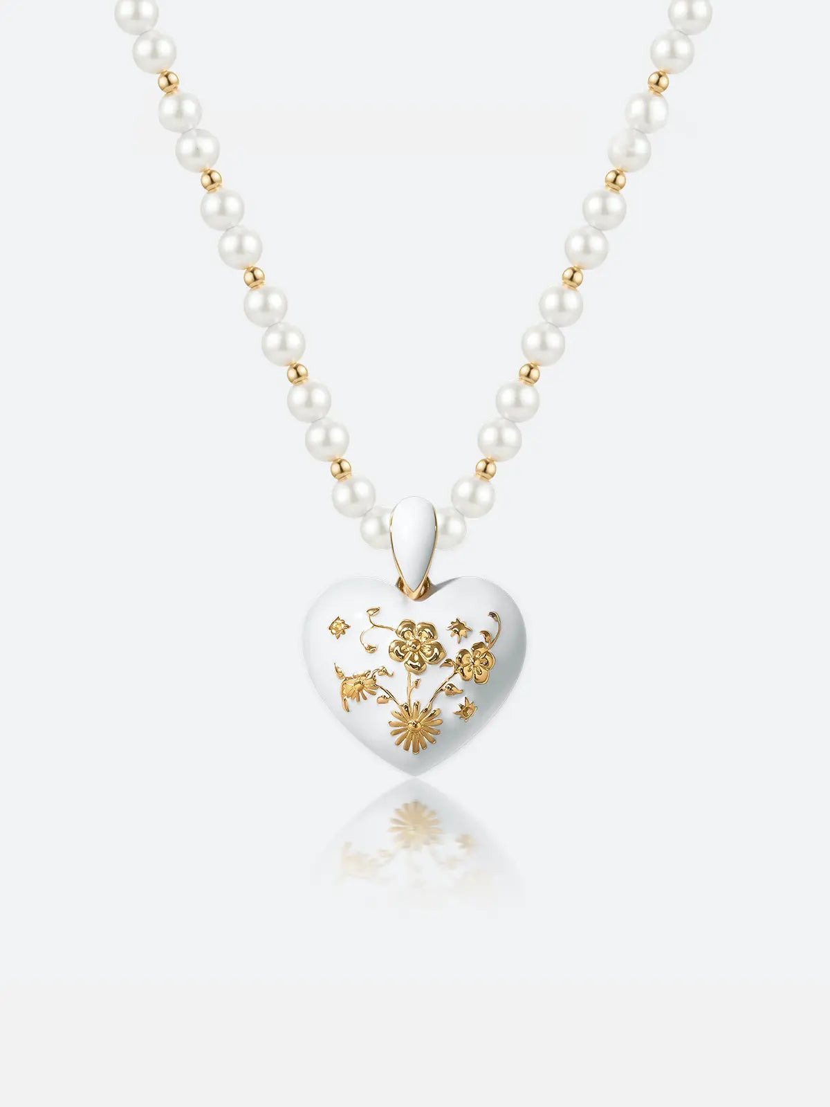 A Tactilery garden floral pearl necklace with a white heart-shaped pendant featuring gold floral engravings, displayed on a clean white background with a soft reflection.