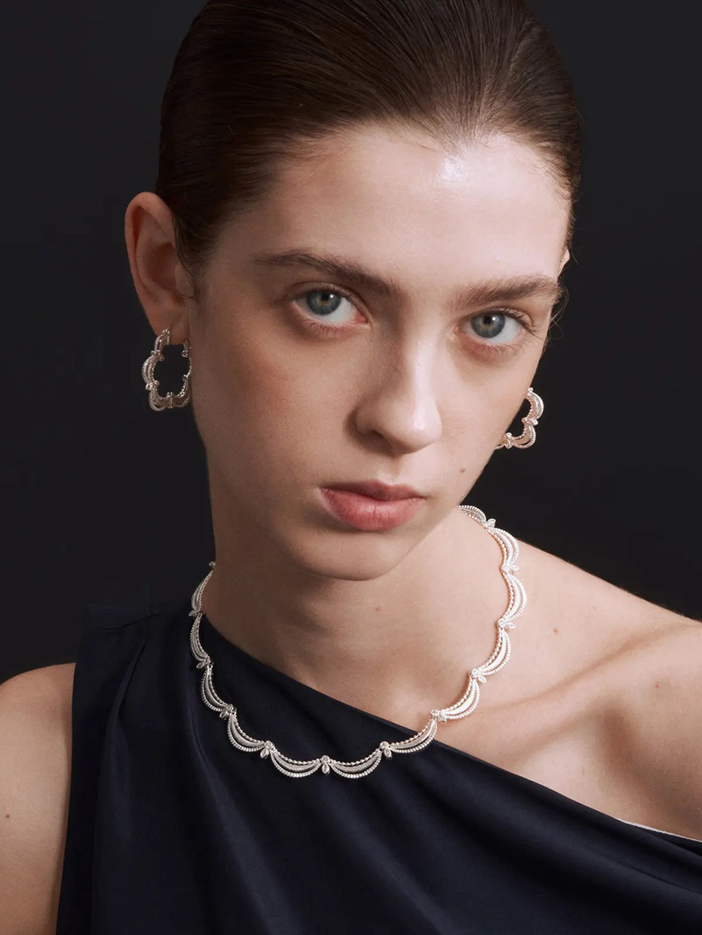 Close-up of the Tactilery Lace Court Necklace on a dark navy velvet surface, the repeating scalloped lace arch links with three concentric matte brushed silver crescent swag bands, continuous ball granulation bead edges, bezel-set round zircon junctions, and prong-set marquise zircon leaf accents shown in detail at a curved angle