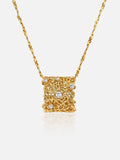 A gold Tactilery lace garden floating necklace with an intricate filigree design and small clear gemstones, shown on a light gray background.