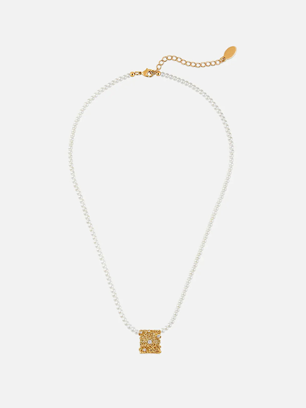 Tactilery Lace Garden Pearl Necklace in polished gold displayed laid out flat on a warm cream surface showing the full necklace length, the fine polished gold twisted petal-link chain extending the full length with the lobster clasp and oval tag charm extension chain at top and the square openwork lace filigree pendant with scattered prong-set round zircons and freshwater baroque pearl drop at bottom center