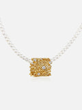 A Tactilery lace garden pearl necklace with a textured gold square pendant adorned with small clear crystals, shown against a light gray background.