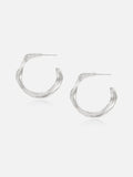 Pair of Tactilery Lake Ripple Hoop Earrings in matte brushed silver on a white background, the large organic C-hoop with a gently undulating wavy silhouette and fine horizontal brushed ripple texture across the wide flat band surface, with silver post pin at top