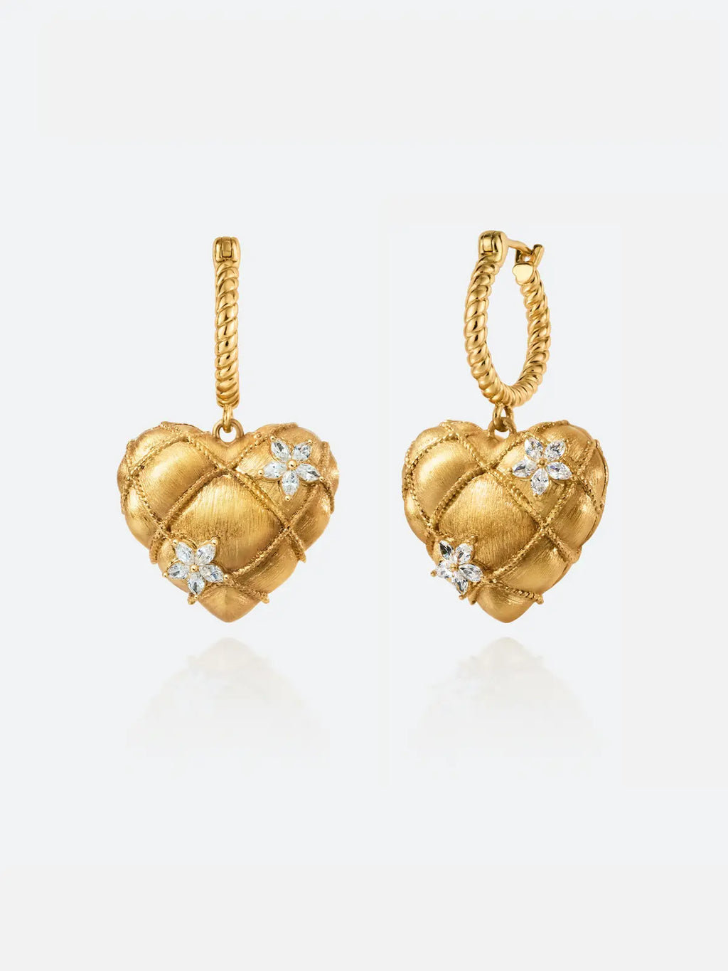Pair of Tactilery Love Blossom Hoop Earrings on a white background, the puffy quilted matte brushed gold heart charm with rope-twist gold wire grid overlay and two prong-set marquise zircon flower clusters, suspended from a twisted rope gold hoop with hinged clasp