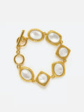 Tactilery Moonlight Box Mother of Pearl Bracelet in polished gold on a white background, the link bracelet composed of seven alternating links — four cushion-square links and three oval links — each with a fine granulated gold milgrain rope border frame set with a large smooth white mother-of-pearl cabochon, connected by small gold jump rings, with a polished gold toggle bar-and-ring clasp