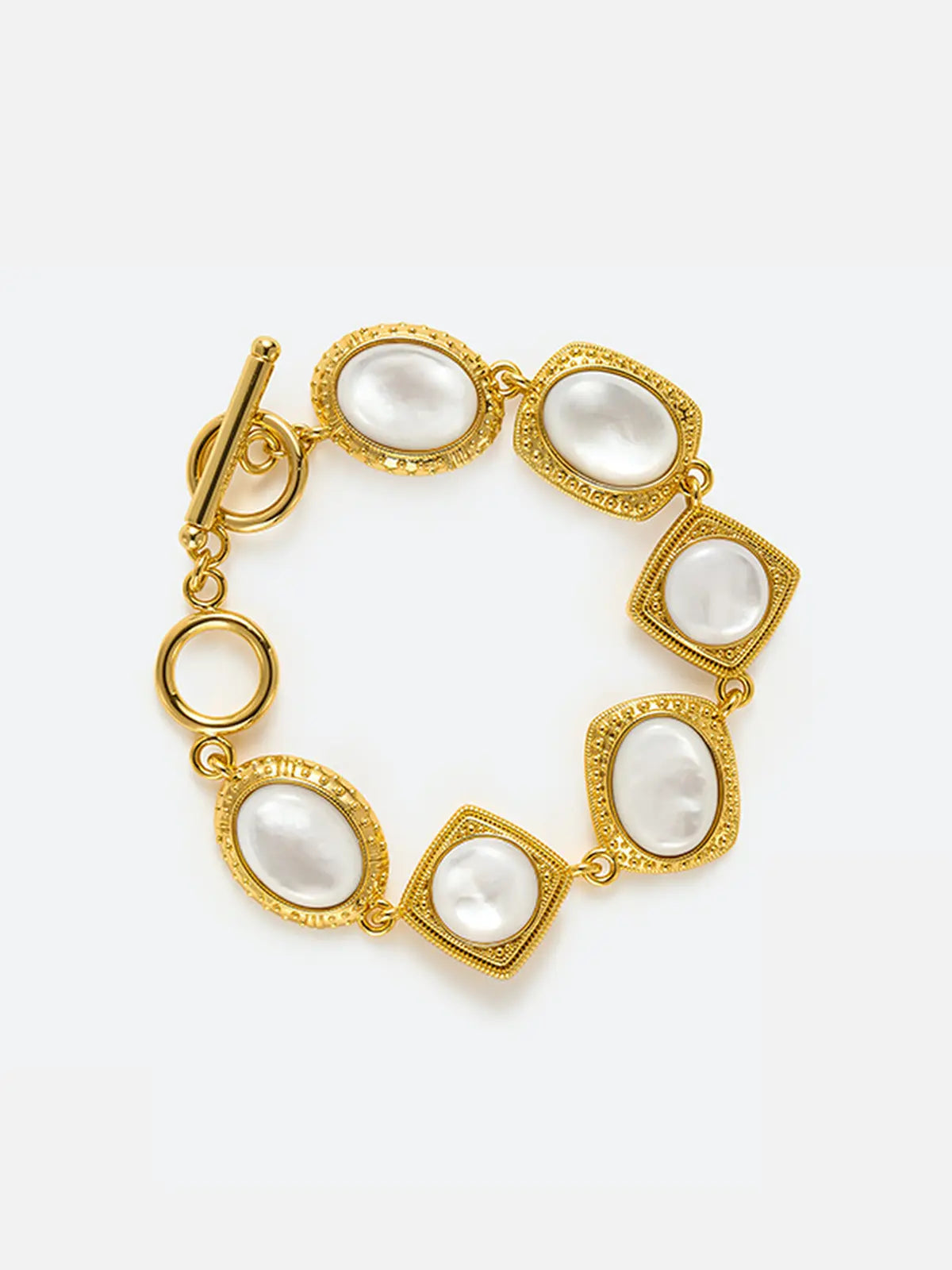 Tactilery Moonlight Box Mother of Pearl Bracelet in polished gold on a white background, the link bracelet composed of seven alternating links — four cushion-square links and three oval links — each with a fine granulated gold milgrain rope border frame set with a large smooth white mother-of-pearl cabochon, connected by small gold jump rings, with a polished gold toggle bar-and-ring clasp
