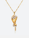 A gold Tactilery bouquet necklace featuring a sculptural lotus flower design adorned with clear gemstones, suspended from a delicate gold chain against a light gray background.