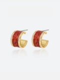 Pair of Tactilery Red Glaze Zircon Hoop Earrings in polished gold on a light grey background, the wide chunky C-hoop with a deep vermilion red crinkled enamel glaze panel inset across the full outer face, bordered above and below by a continuous row of pavé zircon along both gold edges, with silver post pins at top