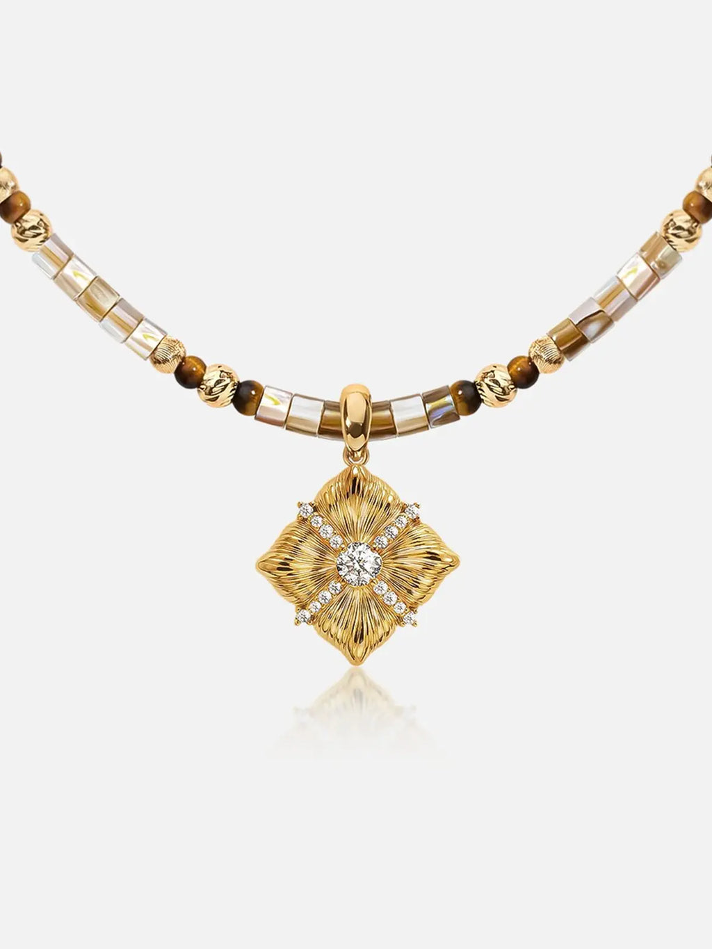 A Tactilery sugar cube beaded necklace featuring a central diamond-shaped pendant with a clear central stone and surrounding gold rays, accented by brown and metallic gold beads on a light gray background.