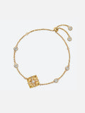 Tactilery Sugar Cube Bracelet in polished gold on a white background, the adjustable slider bracelet with a large square diamond-shaped center pendant — the face deeply ribbed with four radiating petal-like lobes meeting at center, a central prong-set large round zircon, and a pavé zircon cross accent radiating outward along the four lobe dividing lines — suspended on a fine polished gold cable chain with four bezel-set round zircon stations and a gold bead slider with two bezel-set round zircon charm ends