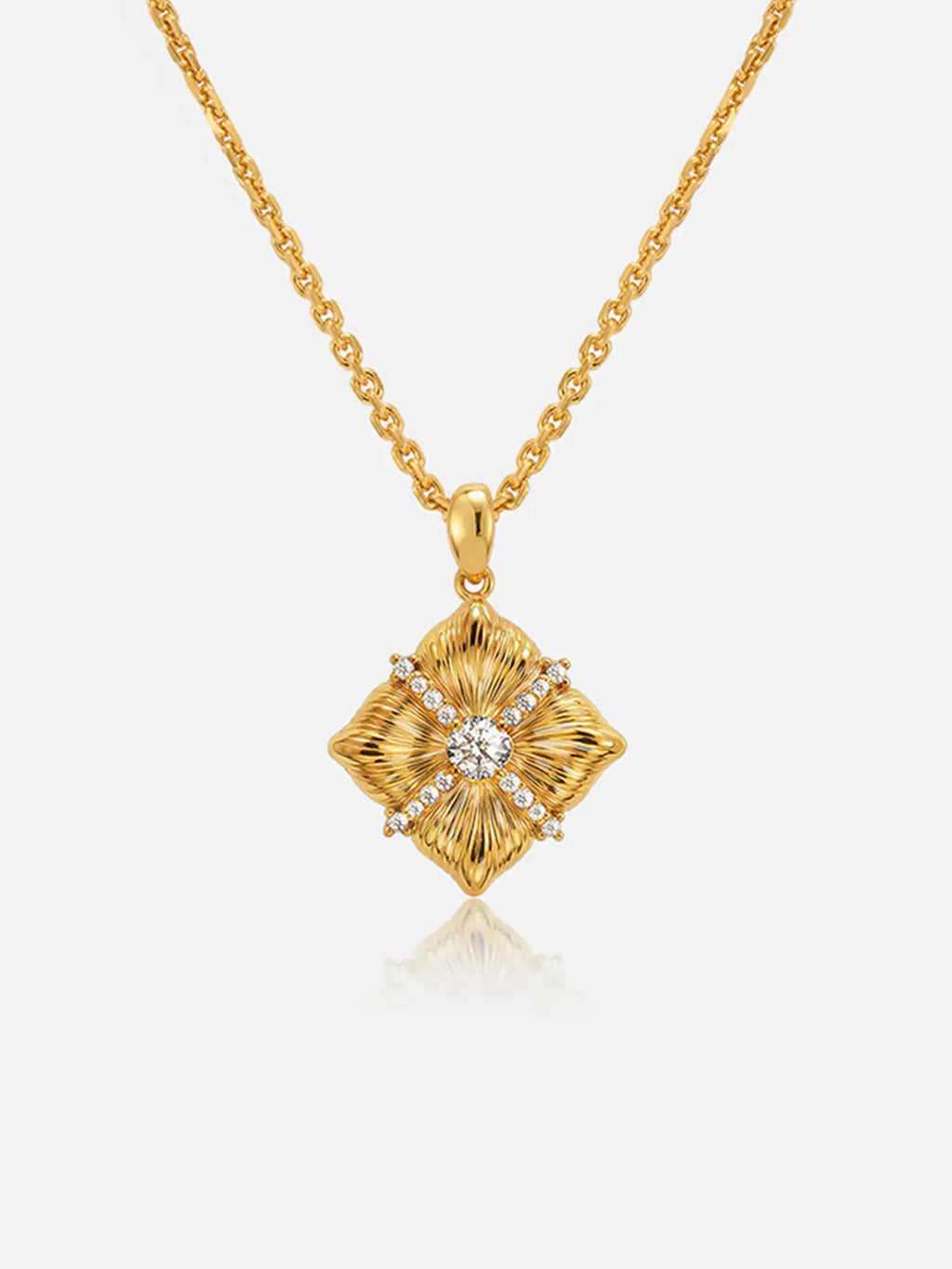 Tactilery Sugar Cube Necklace in polished gold on a white background, the square diamond-shaped pendant with four deeply radiating sunburst line-engraved petal-like lobes meeting at center, a central prong-set large round zircon, and a pavé zircon cross accent radiating outward along the four lobe dividing lines, suspended from a fine polished gold cable chain with a lobster clasp and oval tag charm extension chain