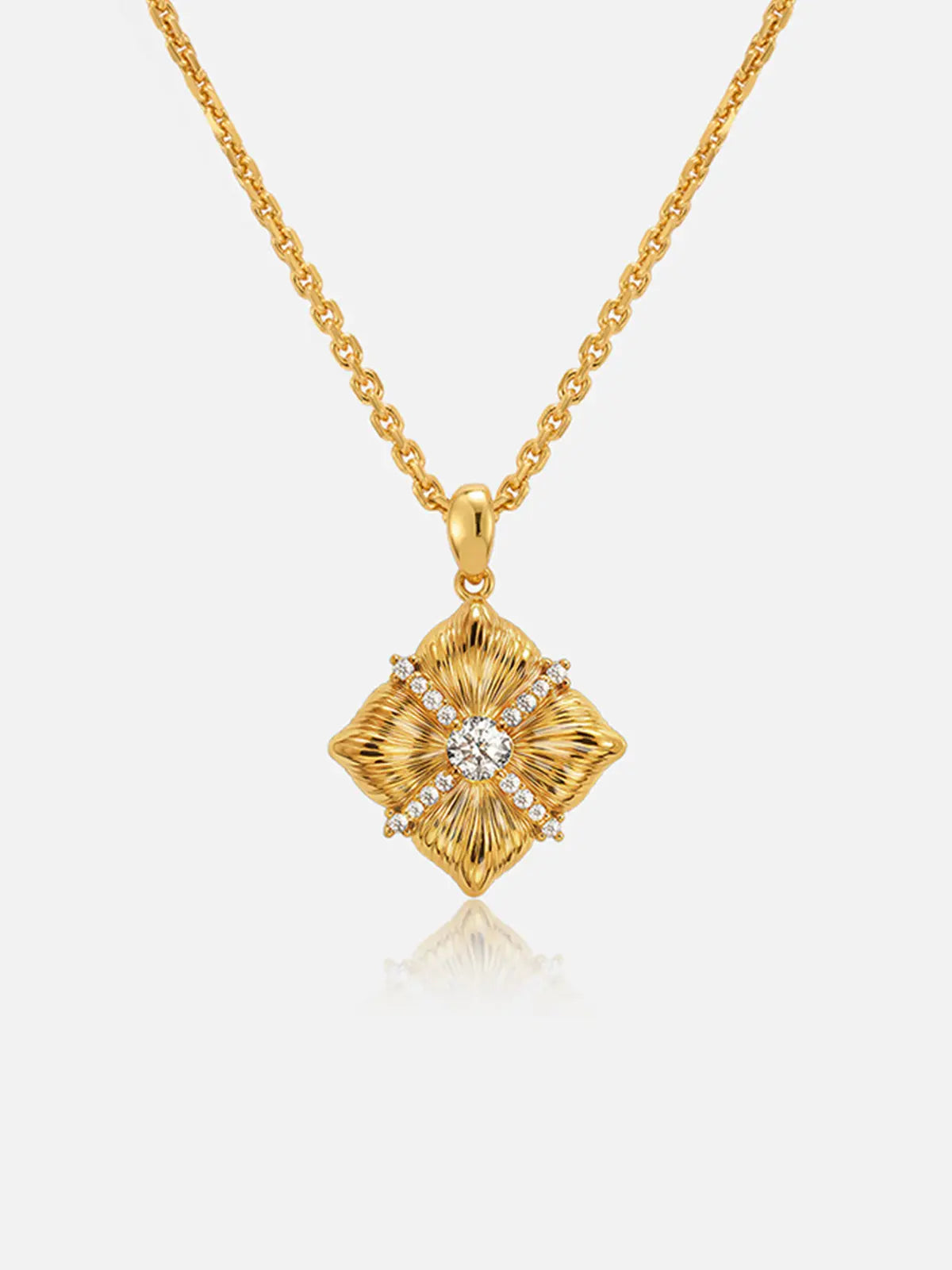 Tactilery Sugar Cube Necklace in polished gold on a white background, the square diamond-shaped pendant with four deeply radiating sunburst line-engraved petal-like lobes meeting at center, a central prong-set large round zircon, and a pavé zircon cross accent radiating outward along the four lobe dividing lines, suspended from a fine polished gold cable chain with a lobster clasp and oval tag charm extension chain