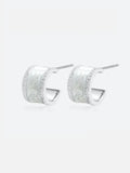 Pair of Tactilery White Glaze Zircon Hoop Earrings on a light grey background, the wide chunky silver C-hoop with a smooth white glaze enamel center panel flanked by two fully pavé zircon rails along the top and bottom edges, with silver post pins