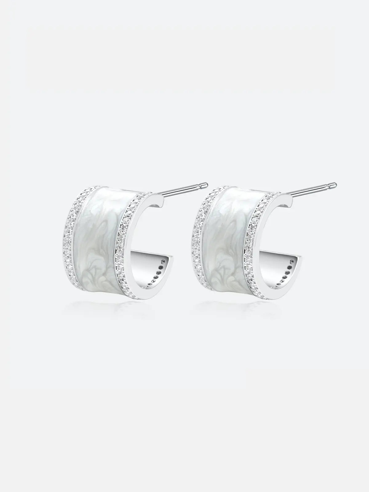 Pair of Tactilery White Glaze Zircon Hoop Earrings on a light grey background, the wide chunky silver C-hoop with a smooth white glaze enamel center panel flanked by two fully pavé zircon rails along the top and bottom edges, with silver post pins